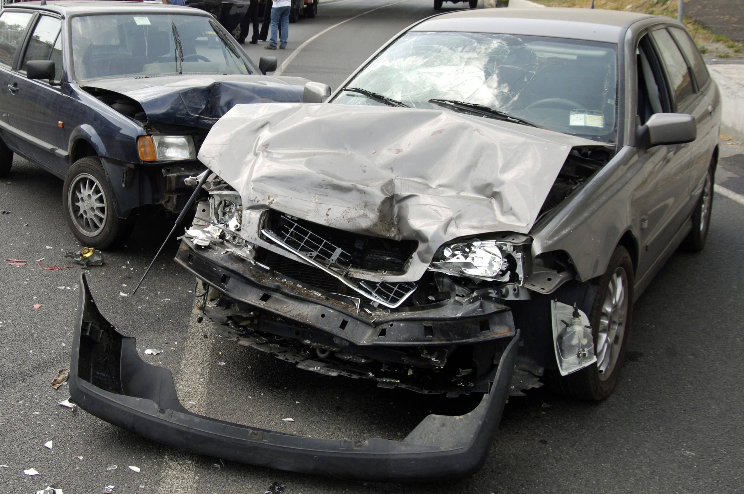 Two heavily damaged cars on a roadway after a front-end collision, with debris scattered around the scene.