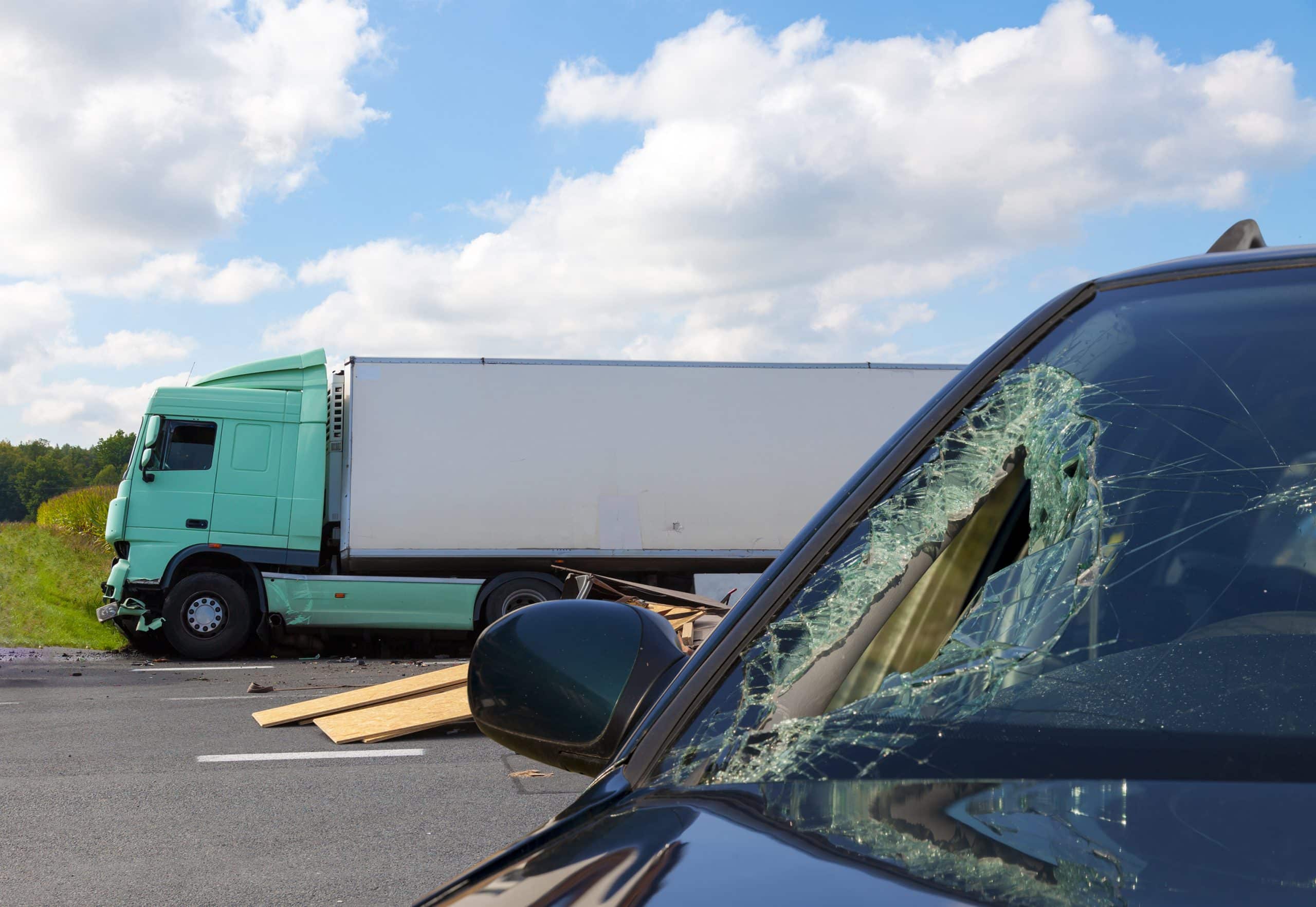 A car with a shattered windshield after a big truck accident.